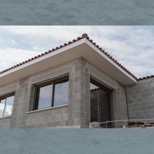 Chantier de villa contemporaine en Corse, gros œuvre en cours avec façade en parpaings et toiture en tuiles en terre cuite.