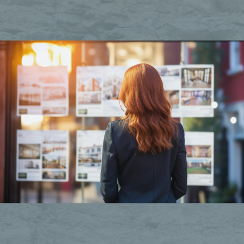 Femme devant la vitrine d’une agence immobilière en Corse, consultant des annonces pour un achat immobilier.