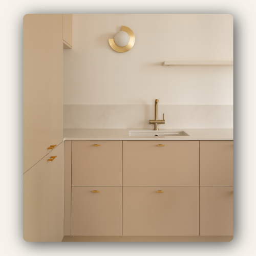 Cuisine design beige avec façades lisses, poignées dorées et robinet en laiton