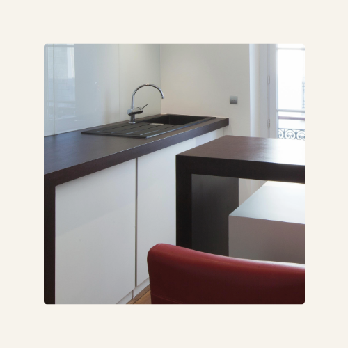 Semi-îlot en épi avec retour snack, plan de travail en bois foncé, façades blanches laquées, évier intégré, design moderne et fonctionnel, Corsica Design, Ajaccio