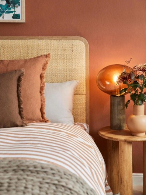 Chambre scandinave avec tête de lit en rotin et bois clair, tons doux et mobilier pastel.