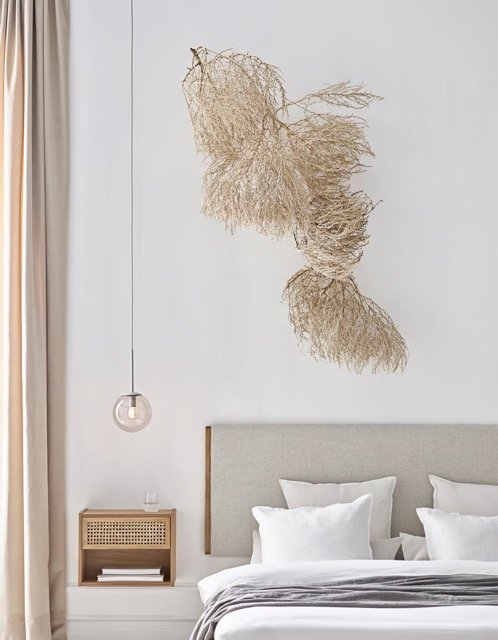 Chambre lumineuse avec tête de lit en bois et tissu beige, décoration minimaliste et naturelle.